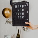person holding a happy new year text on a black board