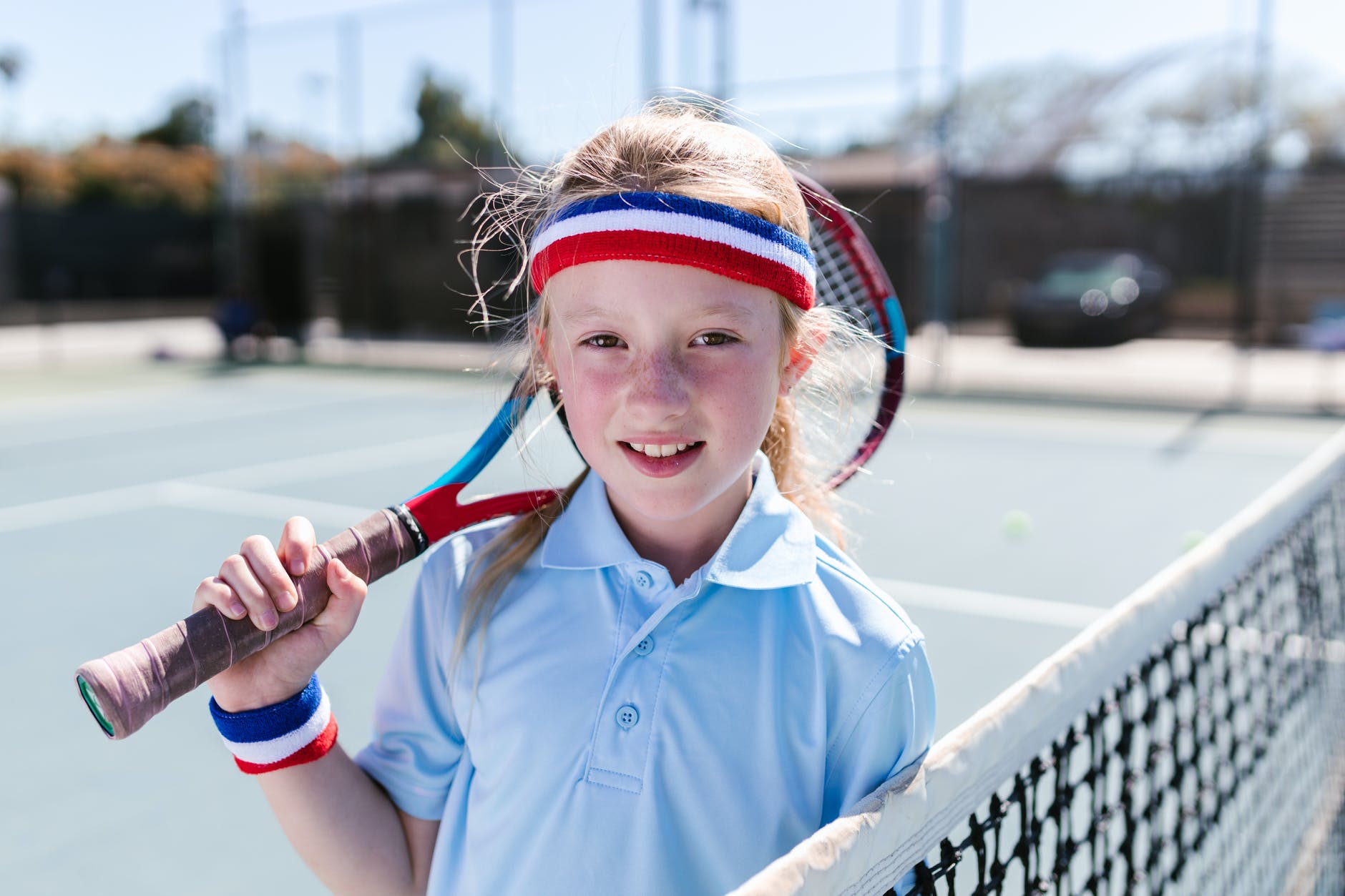 girl wearing sportswear standing by the tennis net